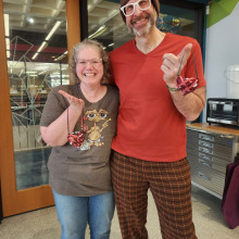 Two artisans holding woven heart baskets.